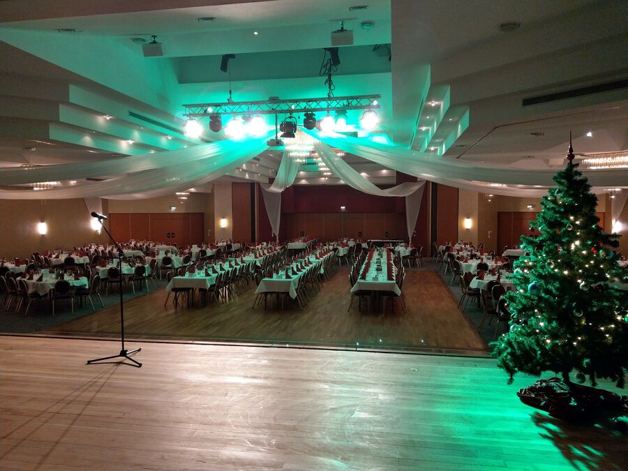 Festlich gedeckter Saal mit Weihnachtsbaum, Blick von der Bühne kurz vor der Zaubershow